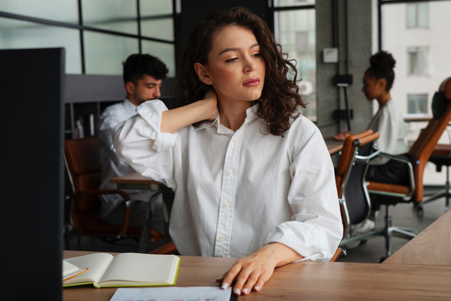 Woman at her desk holding her stiff neck